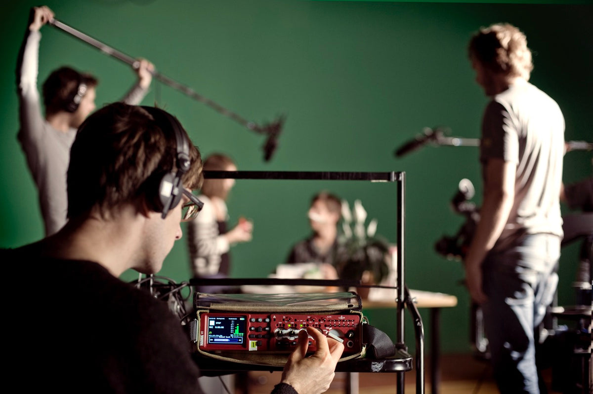 Person operating Nagra audio equipment with a green screen background